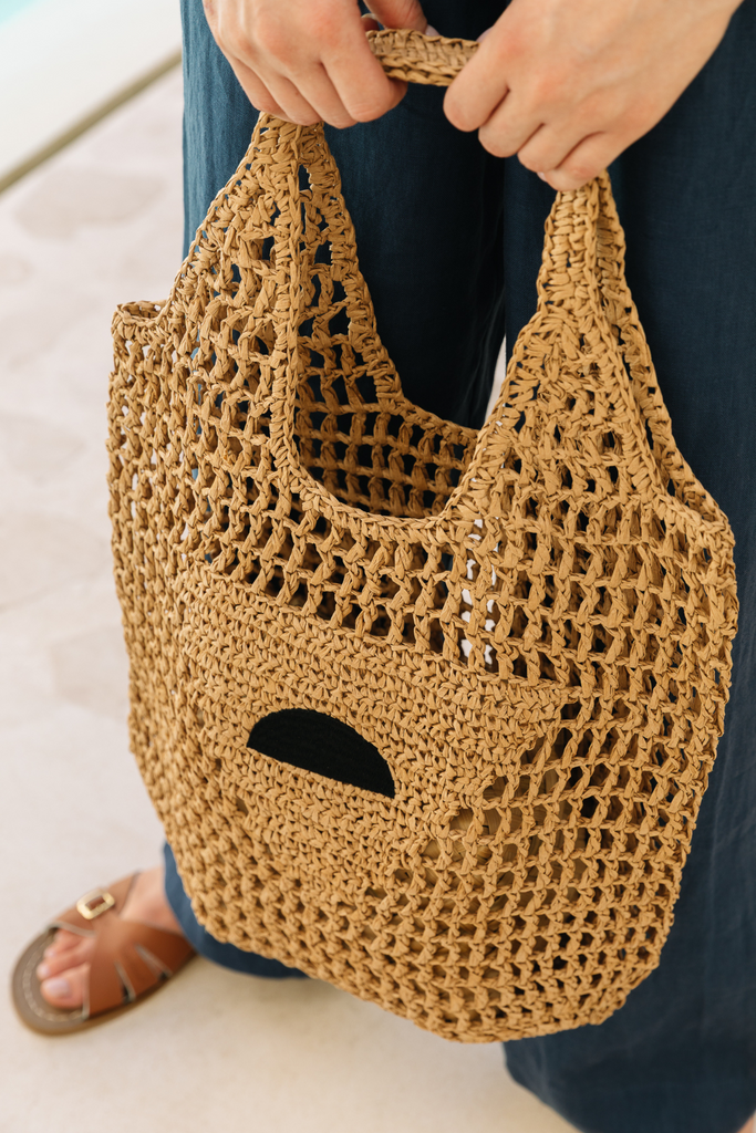 Model holding a raffia beach bag from Summery The Label, styled for a relaxed coastal day in Singapore